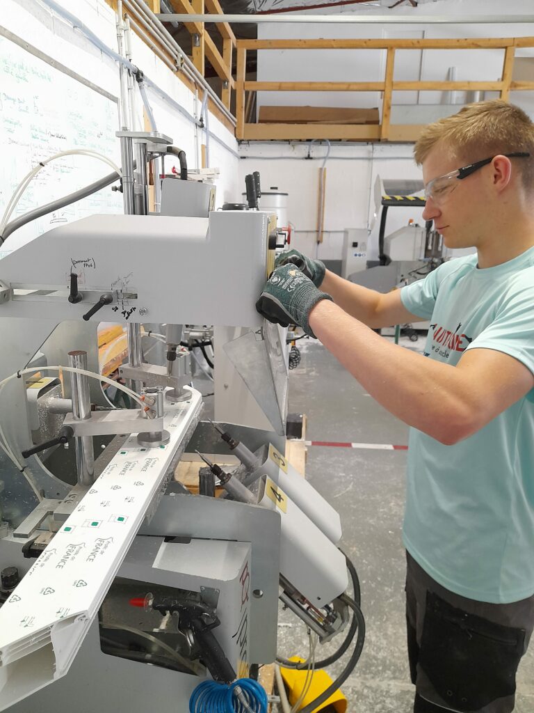 Technicien en atelier réalisant l’usinage de menuiserie PVC sur machine de fabrication sur mesure