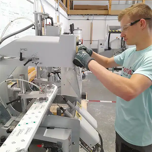 Technicien en atelier réalisant l’usinage d’un profilé PVC pour fabrication de menuiseries sur mesure dans le Cotentin