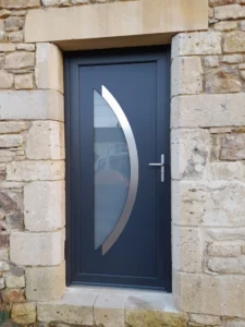 Porte d’entrée gris anthracite avec vitrage décoratif installée sur une maison en pierre dans le Cotentin